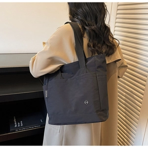 Détail du grand sac cabas noir en toile avec larges bretelles tissées et poche latérale
