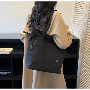Détail du cabas en toile noire avec étiquette tissée et logo CM circulaire brodé