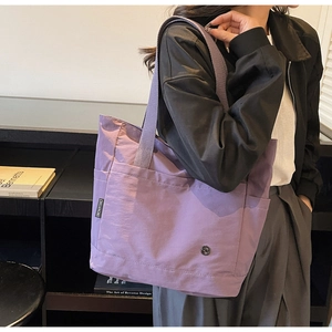 Détail d'un grand sac fourre-tout violet en toile avec étiquette tissée et logo métal