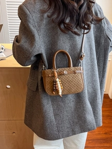 Brown checkered crossbody bag with wooden bead charm worn with a grey blazer