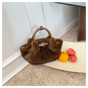Detalle del bolso de peluche marrón con asa de cuero y hebilla metálica de diseño