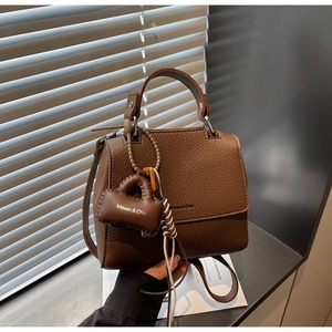 Detail of brown litchi pattern leather handbag with Maven & Chic logo and strap