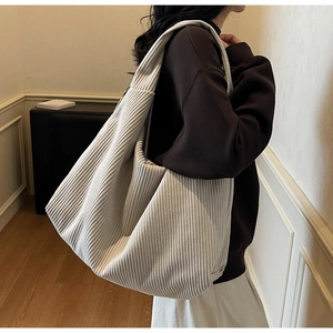 Détail de la texture en velours côtelé beige d'un grand sac cabas porté à l'épaule