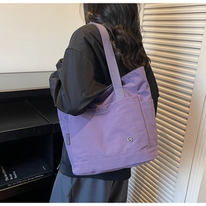 Détail du sac cabas en toile violette avec poche frontale et bandoulière tissée