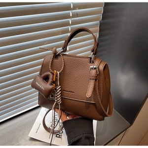 Close-up of brown litchi pattern leather handbag with Maven & Chic brand tag and silver hardware