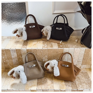 Detailed row of leather bucket bags in brown and black with plush rabbit charms