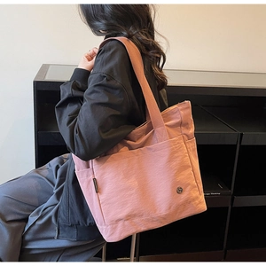 Détail du cabas en toile rose montrant l'étiquette latérale et la poche avant durable
