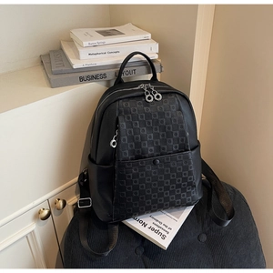 Close-up of black leather backpack with checkered pattern and silver metal zippers