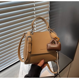 Detail of brown lychee texture leather handbag with silver hardware and logo tag
