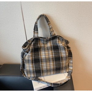 Close-up of thick wool plaid tote bag with top handles and long adjustable shoulder strap