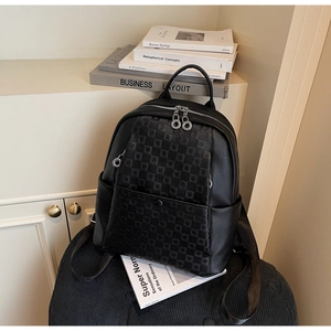 Detail of black pebbled leather backpack showing checkered patterns and silver zippers