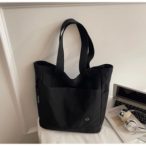 Détail du grand sac cabas noir en toile avec poches latérales et logo pour le bureau