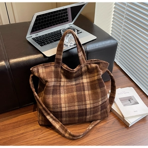 Gros plan d'un sac cabas à carreaux marron en tissu doux avec poignée et bandoulière