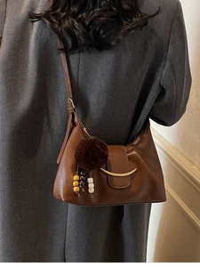 Retro dark brown hobo bag with gold crescent buckle and plush charm on tweed coat