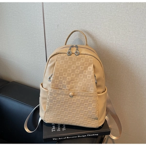 Detail of beige lychee leather backpack showing checkerboard pattern and ring zippers