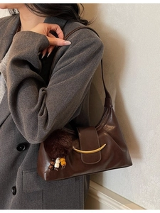 Deep brown leather shoulder bag with gold crescent buckle and plush charm detail