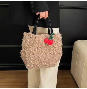 Close-up of fluffy apricot plush bucket bag with black leather handle and cherry charm