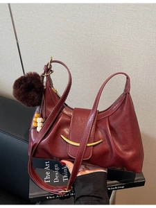 Chic burgundy crescent underarm bag with glossy leather texture and stylish ball charm