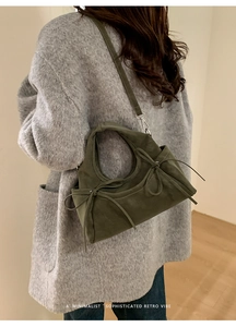 Détail du sac dumpling en daim vert foncé avec nœuds et boucles en métal argenté