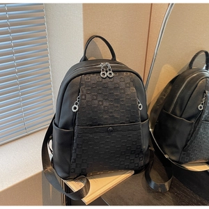 Detail of black leather backpack featuring checkered texture and large metal ring zipper