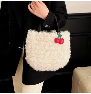Detail of white faux fur bucket bag with black handle and decorative cherry charm