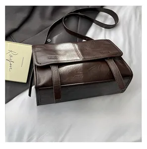 Macro detail of dark brown crinkled leather tote bag with glossy finish and double straps
