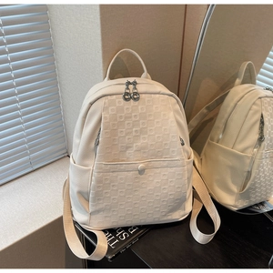 Close-up of cream backpack featuring pebble texture and checkerboard embossed pattern
