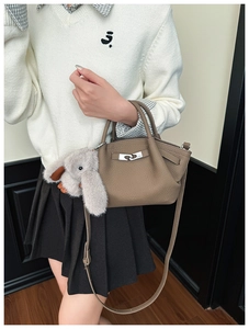 Detail of caramel lychee grain leather bucket bag with silver lock and plush rabbit charm