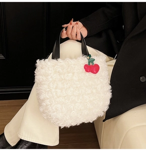 White faux fur bucket bag with black handle and red cherry charm accessory detail