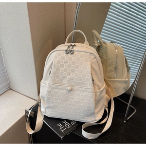 Detail of cream white checkered backpack with dual round zipper pulls and side pocket