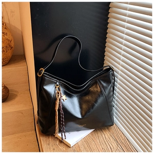 Détail d'un cabas noir brillant avec pendentif étoile et corde tressée sur bois