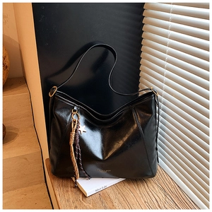 Détail du sac cabas en cuir noir avec breloque étoile et gland tressé sur bois
