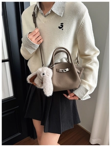 Detail of brown leather bucket bag with silver buckle and plush rabbit charm accessory