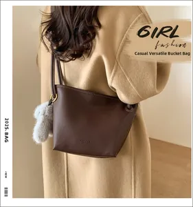Detail of dark brown leather bucket bag with plush charm and golden buckles on wool coat