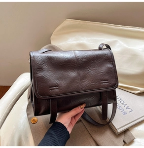 Close-up of vintage dark brown tote bag with textured PU leather and flap closure