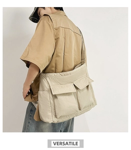 Detail of beige utility messenger bag featuring large front flap pockets and wide shoulder strap