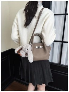 Detail of tan litchi leather bucket bag with silver buckle and plush rabbit charm