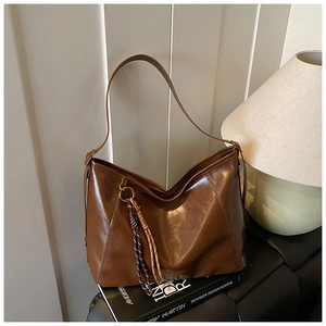 Détail du sac cabas vintage en similicuir ciré marron foncé avec breloque tressée