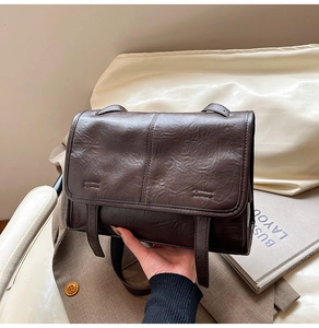 Detail of dark brown vintage tote bag featuring wrinkled leather texture and long straps