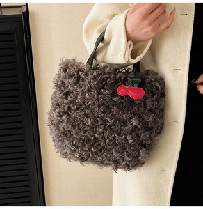 Detail of grey curly faux fur tote bag with a cute red cherry charm and leather handle