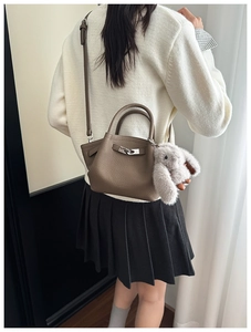 Brown lychee leather bucket bag with metal buckle and plush rabbit charm detail