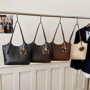 Detalle de bolsos tote en cuatro colores con colgantes de monstruo en un estante
