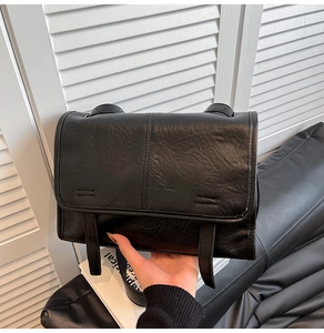 Detail of vintage black PU leather tote with flap cover and rustic buckle straps