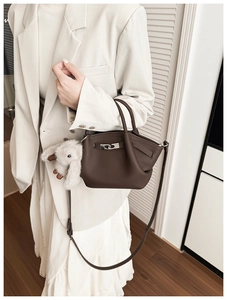 Detail shot of a dark brown pebble leather bucket bag with a cute plush rabbit pendant