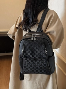 Modern black faux leather backpack with checkerboard texture shown on a model