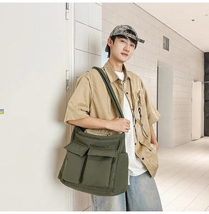 Detail of olive green large canvas messenger bag featuring utility pockets and quilted texture