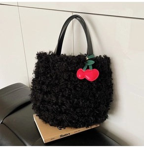 Detail of plush black faux fur bucket bag with leather handles and cherry charm