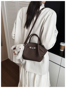 Detail of dark brown pebble leather bucket bag with silver lock and plush bunny charm