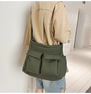 Detail of olive green quilted messenger bag featuring dual large front utility pockets