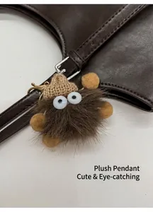 Detalle de un adorno de peluche para bolso con ojos grandes sobre un bolso de cuero